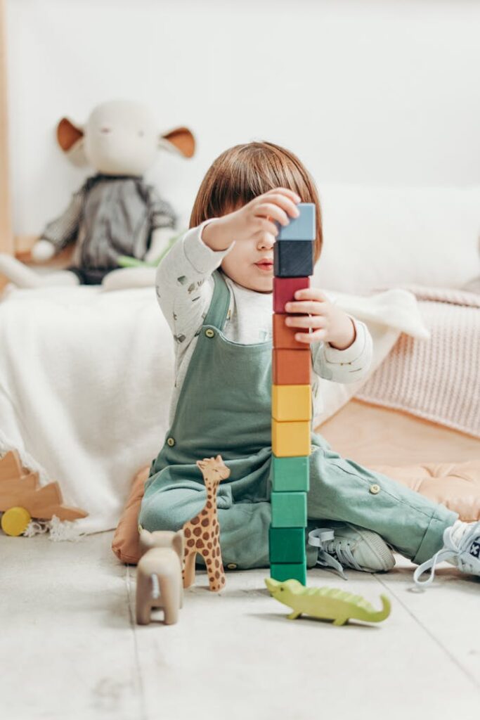 Child in White Long-sleeve Top and Dungaree Trousers Playing With Lego Blocks